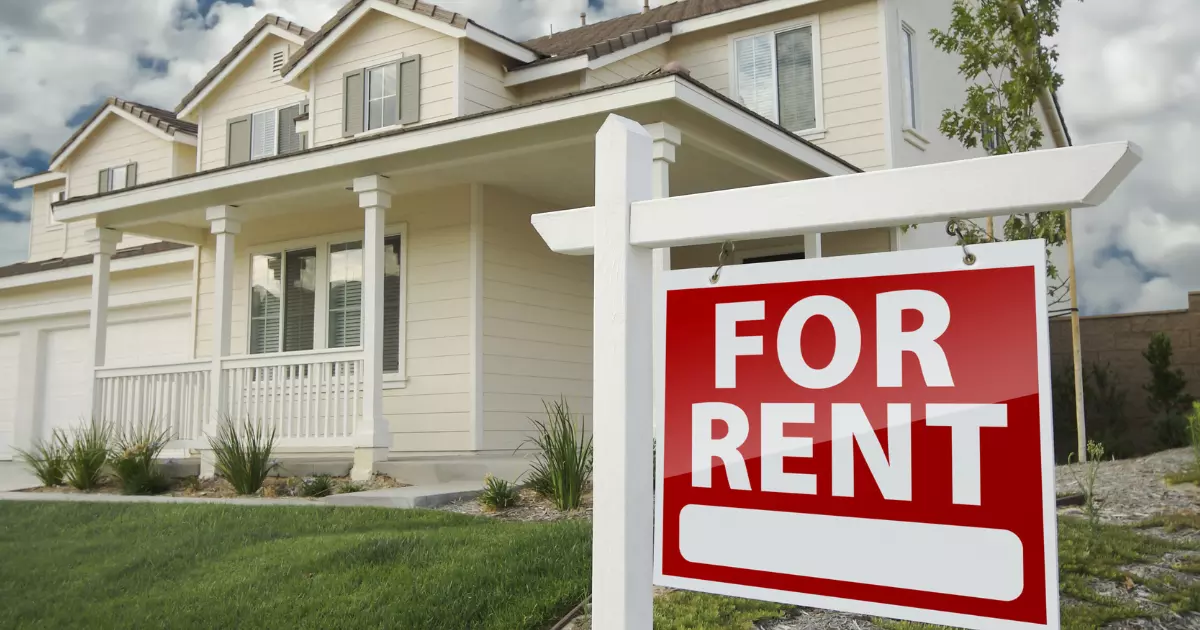 A house with a 'for rent' sign in front of it