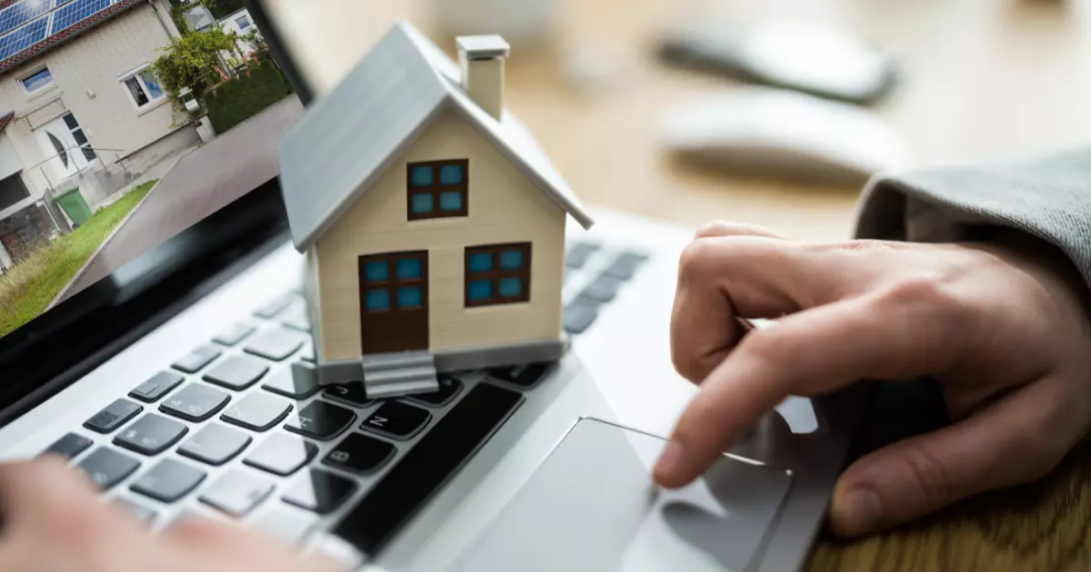 A hand touching a small house on a computer keyboard